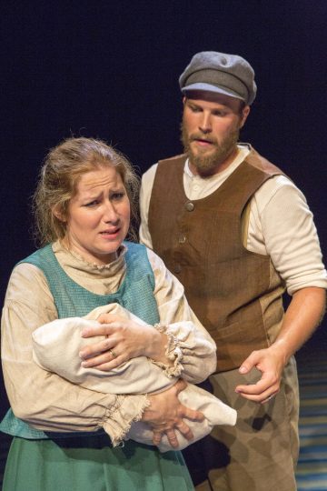 Aikakauden vaatteisiin pukeutunut nainen pitelee vauvaa sylissään ja näyttää ahdistuneelta, ja hänen takanaan seisoo ruskeaan liiviin ja lippikseen pukeutunut parrakas mies, joka ojentaa kätensä huolestuneena. Tausta on tumma ja epäselvä.