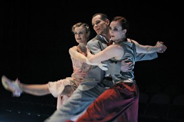 Lavalla esiintyy kolme tanssijaa: harmaapukuinen mies nostaa kaksi naista, joista toisella on vaaleanpunainen mekko ja toisella punaiset housut ja hopeinen toppi. Molemmat naiset ojentavat toisen jalkansa ulospäin poseeratessaan kesken tanssin.