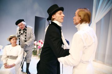 Neljä aikakauden pukuihin pukeutunutta näyttelijää esittää näyttämöllä dramaattisen kohtauksen. Kaksi seisoo kasvotusten etualalla, kun taas yksi istuu ja toinen seisoo takana ja tarkkailee. Lavasteet ovat vähäeleiset, ja taustalla on valkoisia sävyjä ja kukkia.