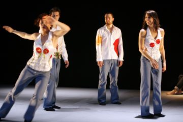 Lavalla esiintyy neljä tanssijaa, joilla on valkoiset topit, joissa on punaisia ja keltaisia kukkakuvioita, ja siniset farkut; yksi tanssija on liikkeessä, kun taas muut seisovat ja hymyilevät, ja taustalla on musta tausta.