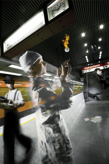 Surrealistinen kohtaus metroasemalla: miimikko jonglööraa liekehtivällä pallolla, sumea juna kulkee ohi, pukumies seisoo, toinen putoaa portaita alas, ja lattialla on hajallaan papereita. Hakanimiemi-kyltti ja kello ovat näkyvissä.