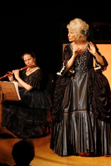 Laulaja, joka on pukeutunut taidokkaaseen, tummaan 1700-luvun pukuun, esiintyy, kun hänen vieressään lavalla istuva muusikko, joka on pukeutunut samaan asuun, soittaa huilua. Tausta on hämärästi valaistu, mikä kiinnittää huomion molempiin esiintyjiin.