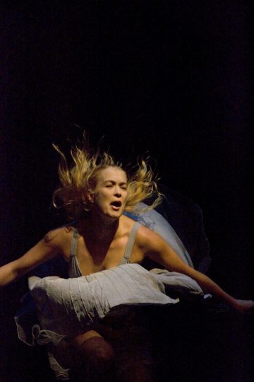 Vaaleat hiukset ja dramaattinen ilme on kuvattu keskellä liikettä tummaa taustaa vasten, ja hänen hiuksensa ja mekkonsa virtaavat ulospäin ikään kuin hän hyppäisi tai tanssisi.