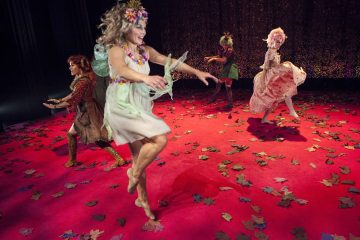 Neljä värikkäisiin, omituisiin pukuihin ja peruukkeihin pukeutunutta ihmistä tanssii paljain jaloin hajallaan olevilla lehdillä ja punaisella matolla päällystetyllä näyttämöllä, jonka taustalla on tumma, kimalteleva verho.