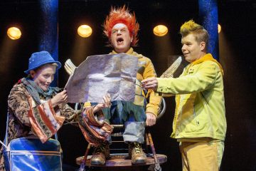 Lavalla esiintyy kolme värikkäisiin pukuihin pukeutunutta näyttelijää; yksi kirkkaan oranssitukkainen istuu korkealla tuolilla kartta kädessään, kun taas kaksi muuta, yksi sinihattuinen ja yksi keltainen, katselevat karttaa elävin ilmein.