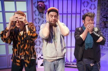 Kolme miestä seisoo peräkkäin, ja jokainen heistä matkii elettä