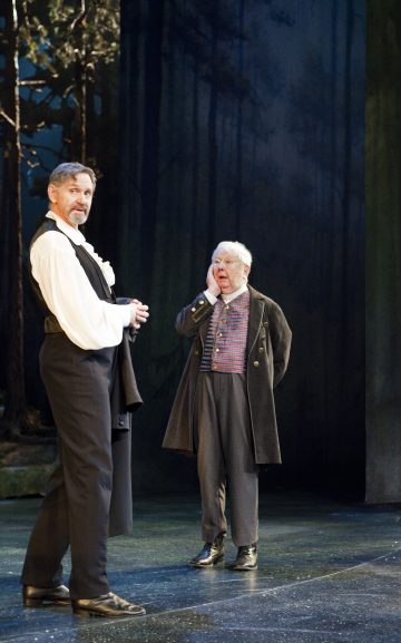 Lavalla esiintyy kaksi aikakauden pukuihin pukeutunutta näyttelijää; toinen seisoo itsevarmasti liivi kainalossaan, kun taas toinen, harmaahiuksinen näyttelijä pitää kättä kasvoillaan yllättyneen näköisenä. Heidän takanaan näkyy metsätausta.