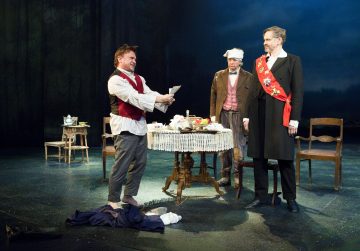 Kolme miestä esiintyy lavalla ruokapöydän ympärillä. Yksi mies, paljain jaloin ja kirje kädessään, näyttää ahdistuneelta. Toisella on yömyssy ja kaapu, ja kolmas seisoo juhlallisesti punaisessa vyötärössä. Tausta on hämärästi valaistu.