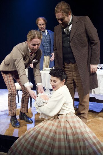 Lavalla esiintyy neljä aikakauden pukuihin pukeutunutta näyttelijää; kaksi miestä auttaa lattialla istuvaa ruutuhameeseen pukeutunutta naista, ja toinen mies seisoo heidän takanaan katsellen. Taustalla näkyy pöytä, jossa on valkoinen liina.