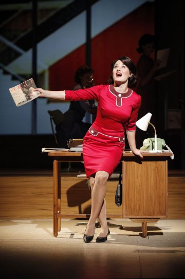 Kirkkaanpunaiseen mekkoon pukeutunut nainen istuu puupöydällä, pitää Vogue-lehteä kädessään ja laulaa intohimoisesti. Hän on näyttämöllä, jossa on dramaattinen valaistus ja rekvisiitta, kuten vanha puhelin ja lamppu.