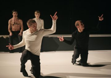 Neljä tanssijaa esiintyy hämärästi valaistulla näyttämöllä; kaksi edessä polvistuu ilmeikkäin käsin, yllään valkoiset ja mustat topit, kun taas kaksi muuta istuu tai polvistuu taustalla, yksi ilman paitaa ja kirjoitus rinnassaan.