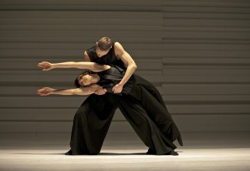 Lavalla esiintyy kaksi nykytanssijaa väljissä mustissa asuissa. Toinen nojaa dramaattisesti eteenpäin kädet ojennettuina, kun taas toinen seisoo takana ja tukee ja pitelee varovasti vyötäröä ja olkapäätä.