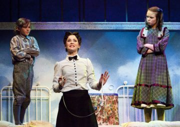 Mary Poppinsiksi pukeutunut nainen seisoo lavalla kahden lapsen välissä. Poika katsoo häntä kädet ristissä, kun taas tyttö, myös kädet ristissä, seisoo sängyn vieressä ja vaikuttaa skeptiseltä. Kohtaus sijoittuu lasten makuuhuoneeseen.
