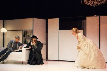 Lavalla esiintyy kolme näyttelijää: yksi makaa valkoisella sohvalla muistikirja kädessään, toinen polvistuu tummassa keskiaikaisessa asussaan, ja kolmas, koristellussa kermanvärisessä puvussa ja kruunussa, nojaa eteenpäin hymyillen kattokruunun alla.