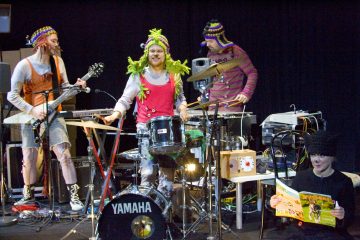 Lavalla esiintyy neljä muusikkoa värikkäissä, omituisissa puvuissa ja neulehattuihin pukeutuneena, ja heillä on soittimia, kuten rumpuja ja kitaroita, kun taas mustiin pukeutunut henkilö istuu lukemassa värikästä kirjaa heidän vieressään.