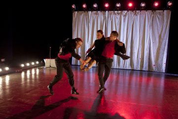 Kolme tanssijaa esiintyy lavalla, jossa on punainen valaistus; kaksi mustiin pukuihin ja punaisiin paitoihin pukeutunutta miestä nostaa mustaan mekkoon pukeutunutta naista, kun he tanssivat valkoisen verhon ja kirkkaiden valonheittimien takana.