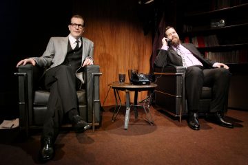 Kaksi miestä istuu tuoleilla.