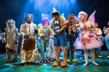 Kirkkaiden sinisten valojen alla lavalla seisoo joukko värikkäisiin satu- ja pelleasuihin pukeutuneita näyttelijöitä, kuten kissa, klovni, Pinokkio, piparkakkumies ja keiju.