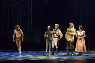 Lavalla esiintyy viisi näyttelijää; yksi heistä on pukeutunut Tarzaniksi lannevaatteeseen ja erottuu neljästä muusta tutkimusmatkailijan asuun pukeutuneesta näyttelijästä. Tausta on tumma, ja lattialla on värikäs näyttämövalaistus.