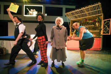 Neljä värikkäisiin ja omituisiin pukuihin pukeutunutta näyttelijää esiintyy tarmokkaasti näyttämöllä eloisan välipalakojun edessä, ja yksi heistä pitää kädessään kylttiä, jossa lukee 