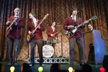 Lavalla esiintyy viisi punaisiin bleisereihin pukeutunutta muusikkoa, joilla on kitarat, rummut ja koskettimet. Rumpukapulassa lukee 