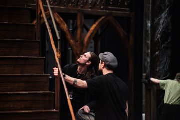 Näyttämömiehiä lavalla pystyttämässä lavasteita