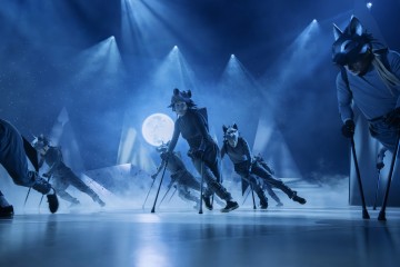 Sudenpukuiset esiintyjät tanssivat sinisten näyttämövalojen alla täysikuun taustan, sumuefektien ja geometristen lavasteiden kanssa luoden mystisen, yöllisen tunnelman.