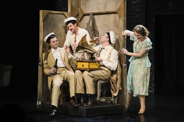 Lavalla esiintyy neljä vintage-asuihin pukeutunutta näyttelijää, kolme merimieshattupäistä miestä istuu vanhan gramofonin ympärillä nauraen ja juomia kädessään, ja vaaleanvihreään mekkoon pukeutunut nainen kurkistelee leikkisästi puisen kuvaruudun takaa.