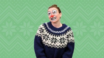 Sinivalkokuvioiseen villapaitaan pukeutunut henkilö poseeraa hymyillen. Hänellä on liioiteltu klovnimeikki, johon kuuluu valkoista kasvomaalia, suuri punainen nenä ja leveä, mustalla reunustettu suu. Taustalla on vihreä talvinen villapaitakuvio.