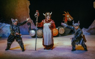 Lavalla esiintyy kolme näyttelijää taidokkaissa viikinkipuvuissa; keskimmäisellä esiintyjällä on sarvikypärä, punainen turkki ja sauva kädessään, ja muut poseeraavat tarmokkaasti. Taustalla näkyy viikinkilaivan rekvisiitta.