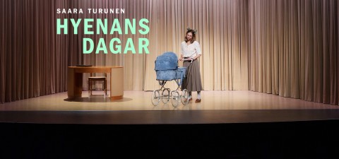 Eläinkorvainen nainen seisoo lavalla vanhanaikaisten sinisten lastenvaunujen vieressä. Hänen vasemmalla puolellaan on puinen kirjoituspöytä ja tuoli. Taustalla on beige verho. Tekstissä lukee: SAARA TURUNEN HYENANS DAGAR.