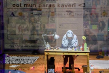 Huppariin pukeutunut henkilö istuu sotkuisessa huoneessa sotkuisen puisen työpöydän ääressä, pää käsissä. Päällekkäin on suomenkielisiä tekstiviestejä ja kuvakkeita, muun muassa oot mun paras kaveri <3 (you are my best friend <3).