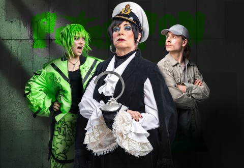 Kolme pukumiestä poseeraa dramaattisesti. Yhdellä on kirkkaanvihreä peruukki ja takki, toinen on pukeutunut merirosvoksi koukkukädellä ja kapteeninhatulla, ja kolmannella on harmaa lippis ja takki, kädet ristissä, graffitiseinää vasten.