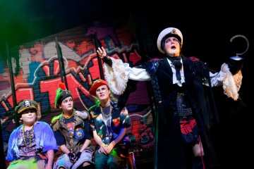 Lavalla esiintyy neljä värikkäisiin asuihin pukeutunutta henkilöä; kolme istuu penkillä merirosvoiksi pukeutuneina, kun taas yksi seisoo koukkukädellä, valkoinen hattu päässä ja dramaattinen ilme kasvoillaan. Taustalla on graffitin peittämä tiiliseinä.