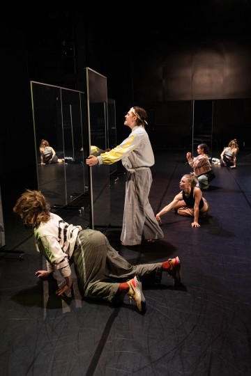 Neljä tanssijaa esiintyy pimeällä näyttämöllä, jossa on suuret lasipaneelit. Kaksi on kyyristynyt lattialle, yksi nojaa paneelia vasten ja katsoo ylöspäin, ja toinen istuu takana, kaikki ekspressiivisissä, dramaattisissa asennoissa.