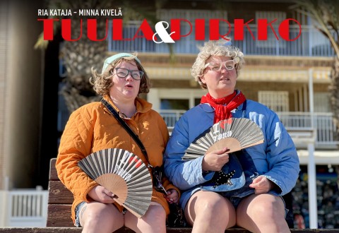Kaksi naista, joilla on silmälasit, värikkäät takit ja huivit, istuu ulkona penkillä, ja kummallakin on kädessään tuuletin. He katsovat sivulle, ja heidän yläpuolellaan lukee teksti "TUULA & PIRKKO".