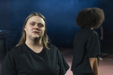 Etualalla seisoo nainen, jolla on kyyneleet silmissä, musta paita yllään ja tunteellinen katse. Taustalla seisoo toinen kiharatukkainen henkilö, joka on myös pukeutunut mustaan, kasvot poispäin. Kohtaus on hämärästi valaistu sinisellä usvalla.